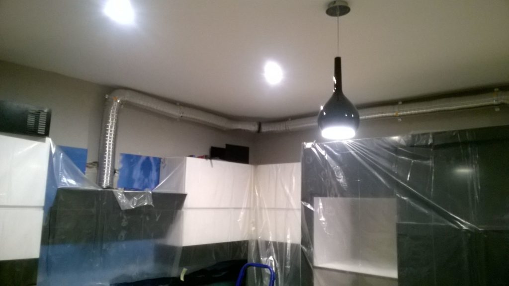 Czarna lampa wisząca i włączone oświetlenie w remontowanym wnętrzu.