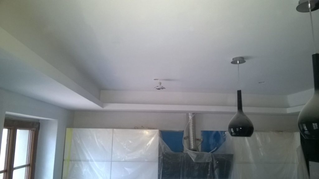 Sufit w remontowanym wnętrzu z odsłoniętą instalacją i folią zabezpieczającą.