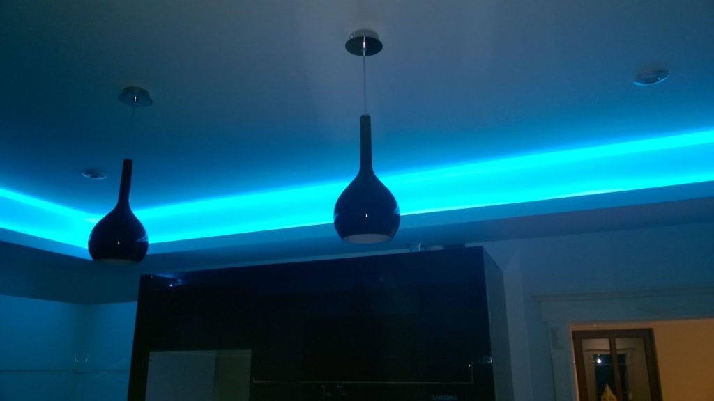 Czarna lampa wisząca na tle niebieskiego oświetlenia LED.