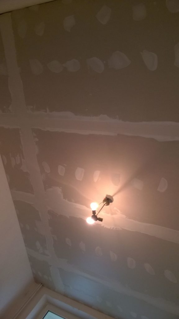 Sufit z płyt gipsowo-kartonowych i pojedynczą żarówką.