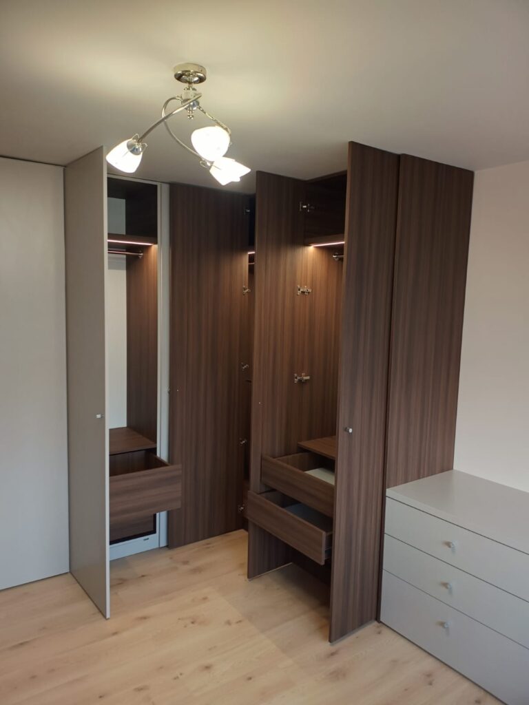 Drewniana zabudowa meblowa z oświetlonymi półkami.