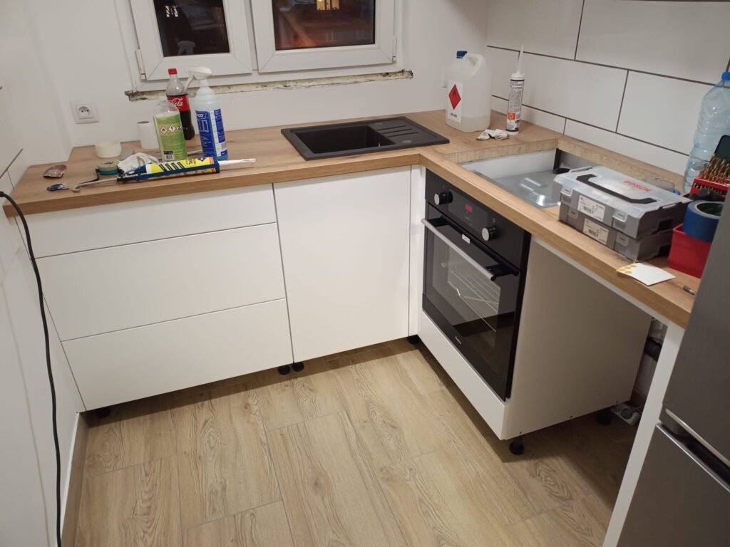 Biała kuchnia z drewnianym blatem i piekarnikiem.