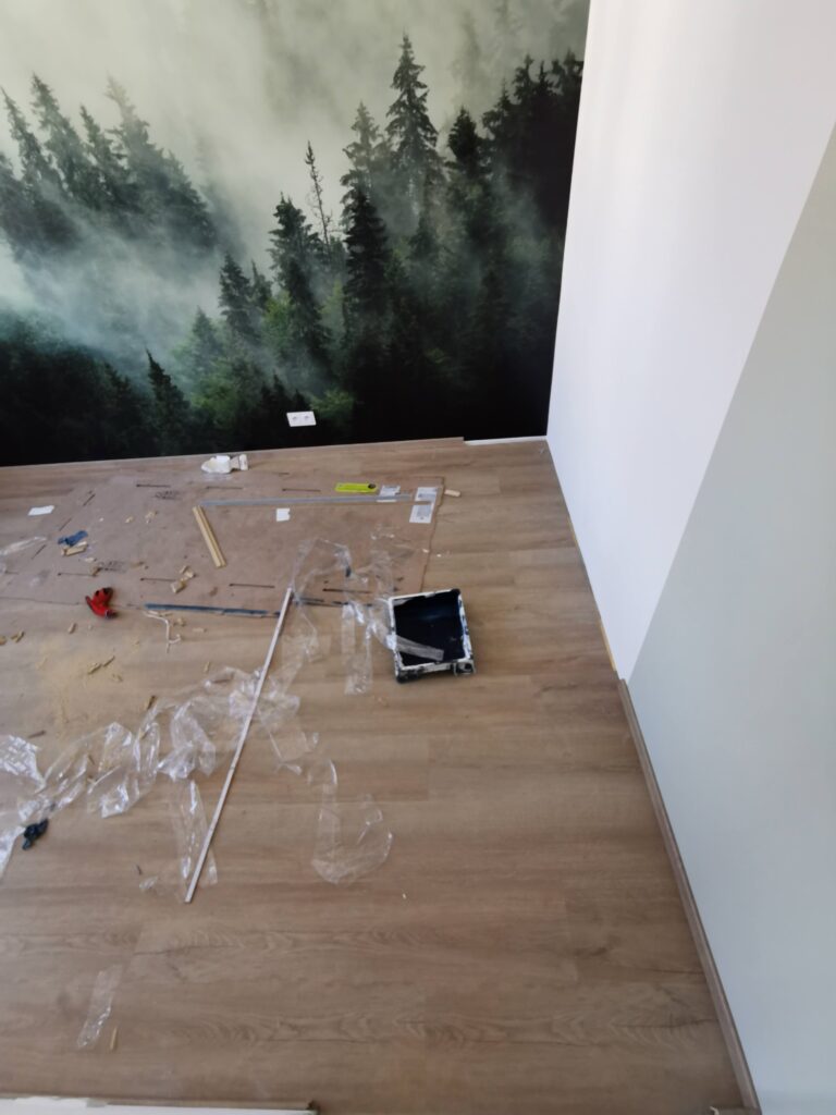Remontowany pokój z leśną fototapetą i narzędziami na podłodze