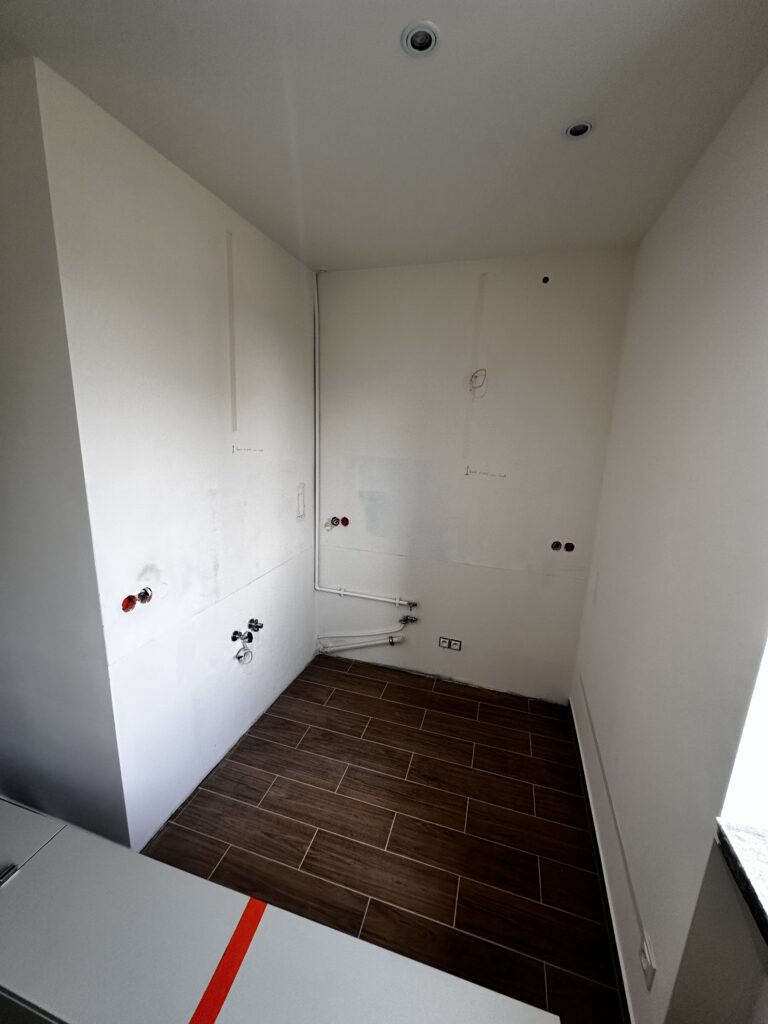 Pomieszczenie z białą zabudową i przygotowanymi przyłączami.