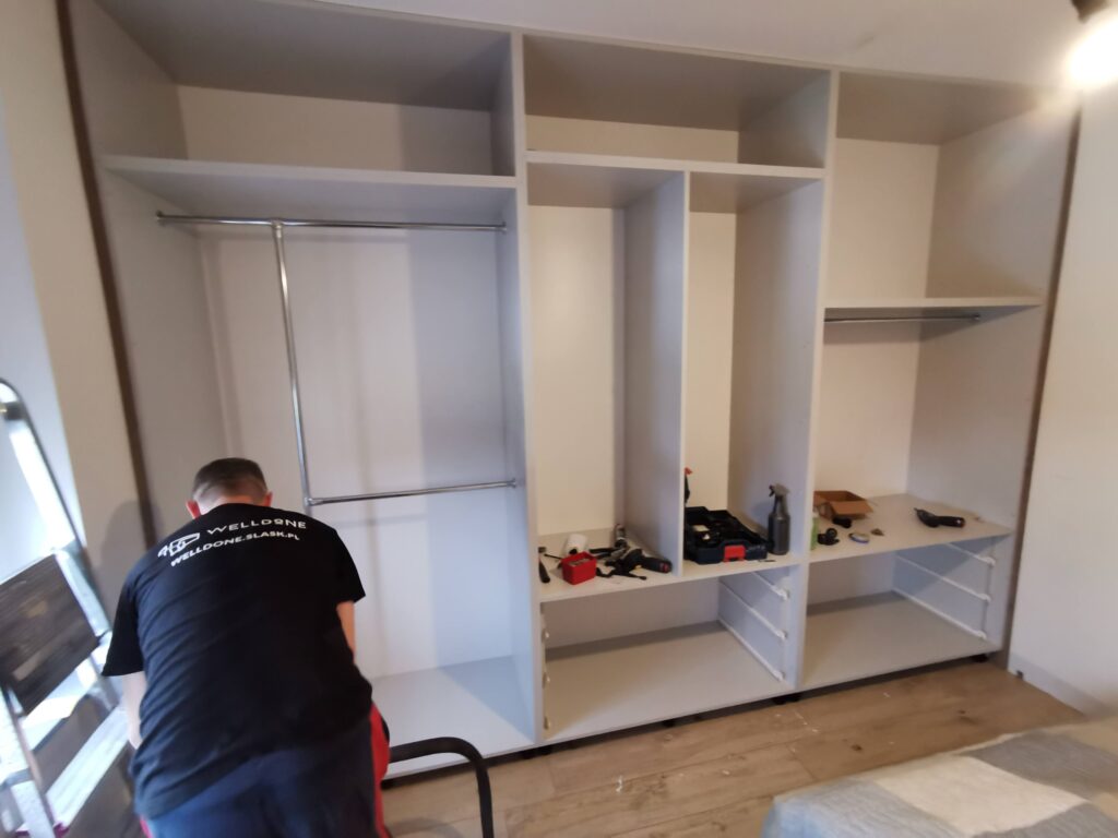 Mężczyzna odkurzający podłogę przed szafą w sypialni