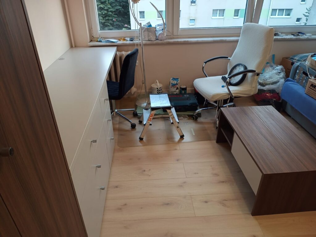 Jasny pokój z biurkiem przy oknie.