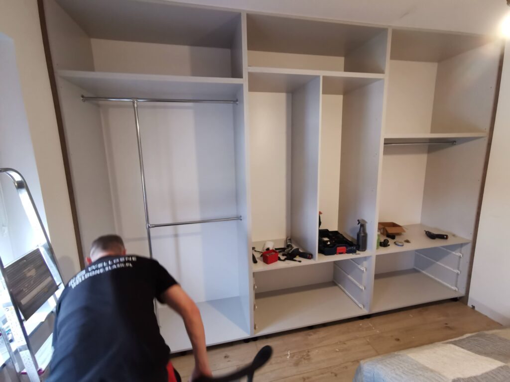 Biała szafa z półkami i drążkami podczas sprzątania wnętrza