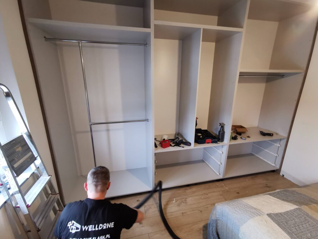 Mężczyzna sprzątający podłogę obok otwartej szafy i drabiny