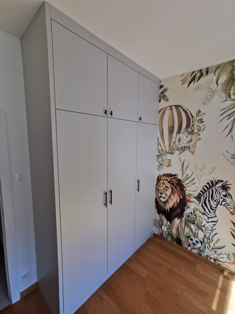 Biała szafa z czarnymi uchwytami przy fototapecie ze zwierzętami