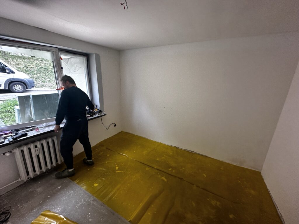 Mężczyzna pracuje przy oknie w pustym pomieszczeniu.