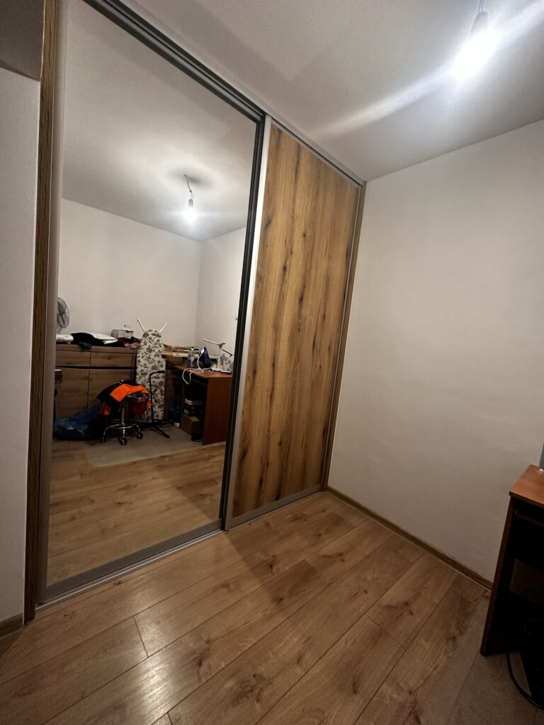 Szafa z lustrem i drewnianymi drzwiami przesuwnymi.