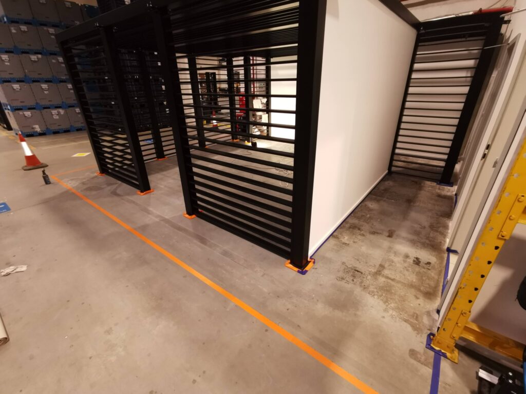 Czarne metalowe ścianki działowe na betonowej podłodze.