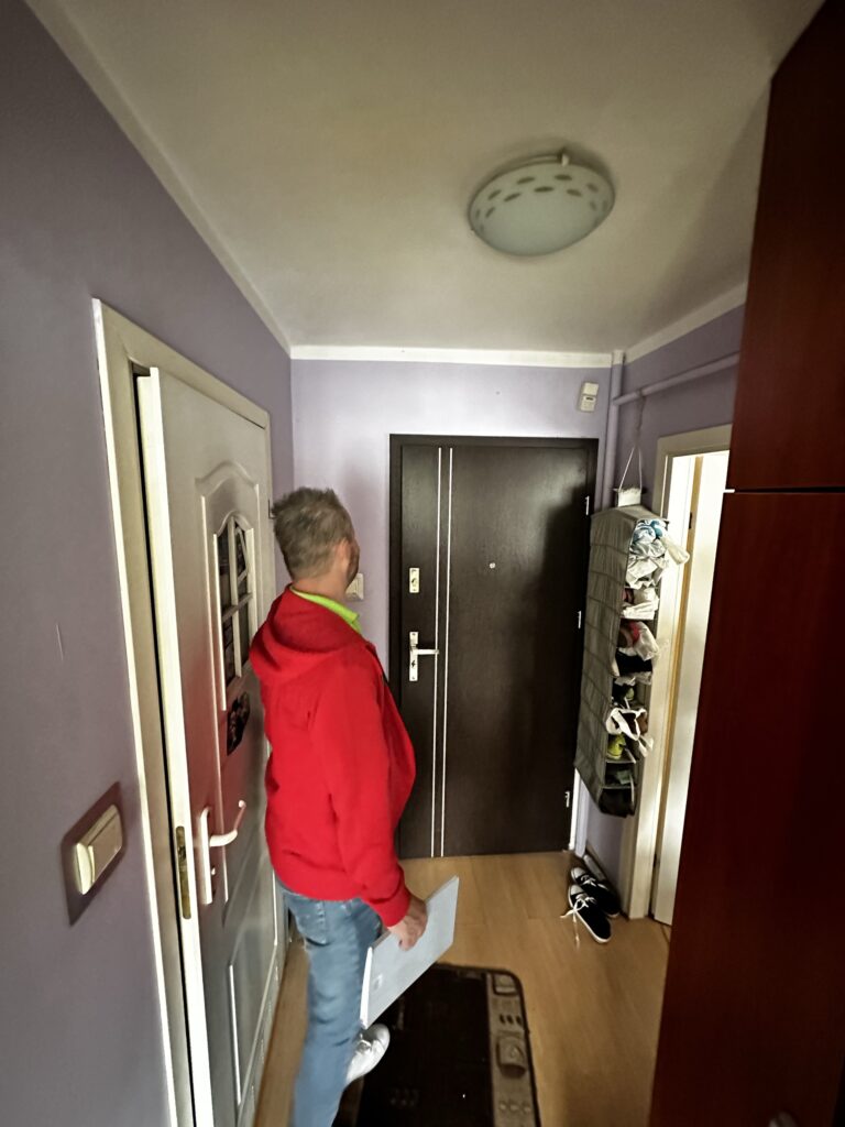 Mężczyzna w czerwonej bluzie w korytarzu mieszkania.