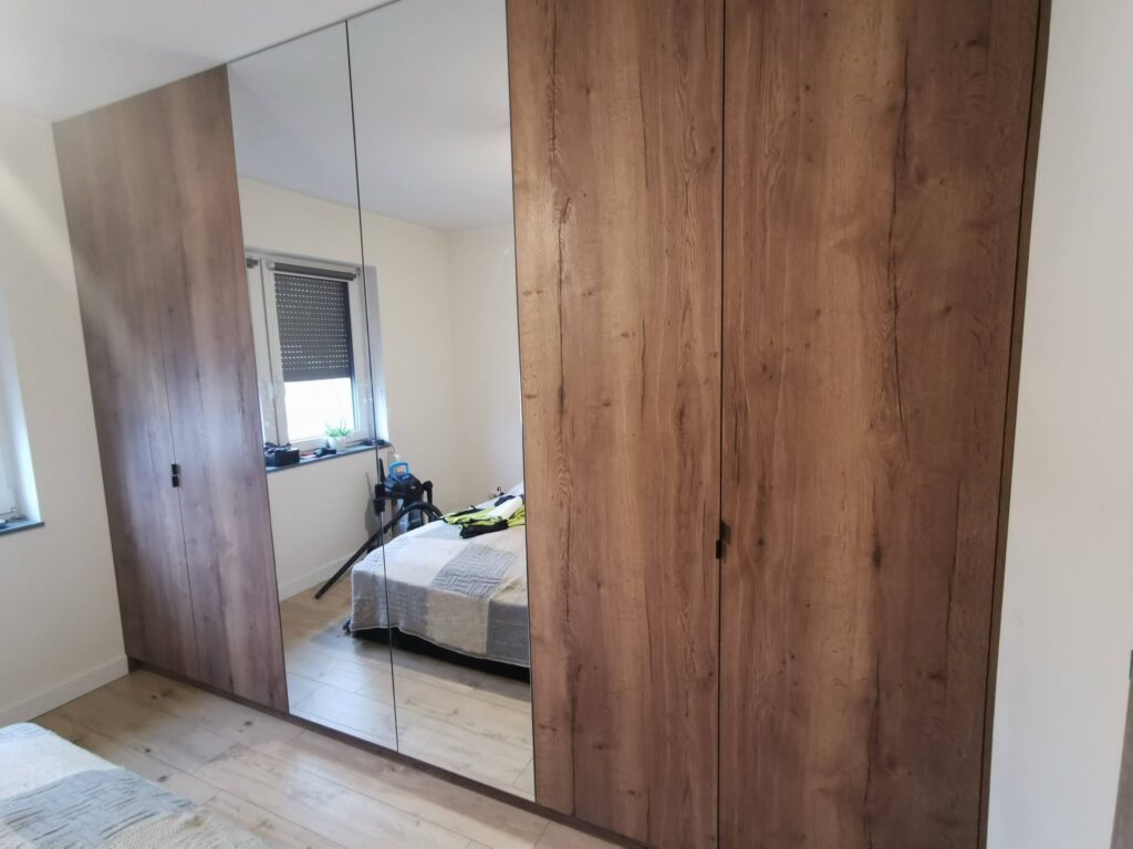 Duża szafa z drewnianymi drzwiami i lustrzanym panelem pośrodku