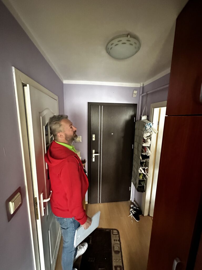 Mężczyzna w czerwonej bluzie w korytarzu mieszkania.