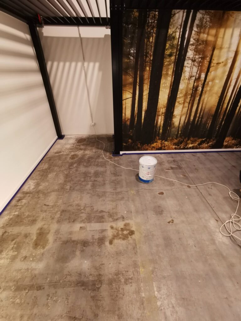Betonowa podłoga w pomieszczeniu z fototapetą lasu.