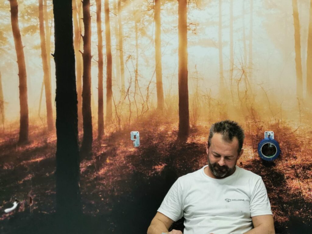 Mężczyzna siedzący przed ścianą z fototapetą przedstawiającą las.