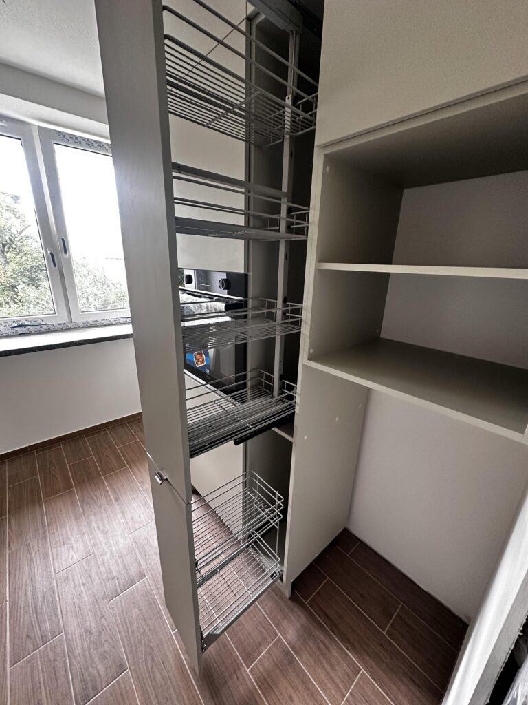 Otwarta szafa z wysuwanym koszem i półkami.