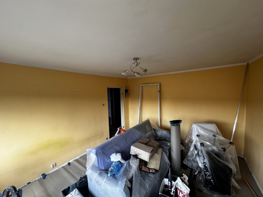 Żółty pokój w trakcie remontu z materiałami budowlanymi.