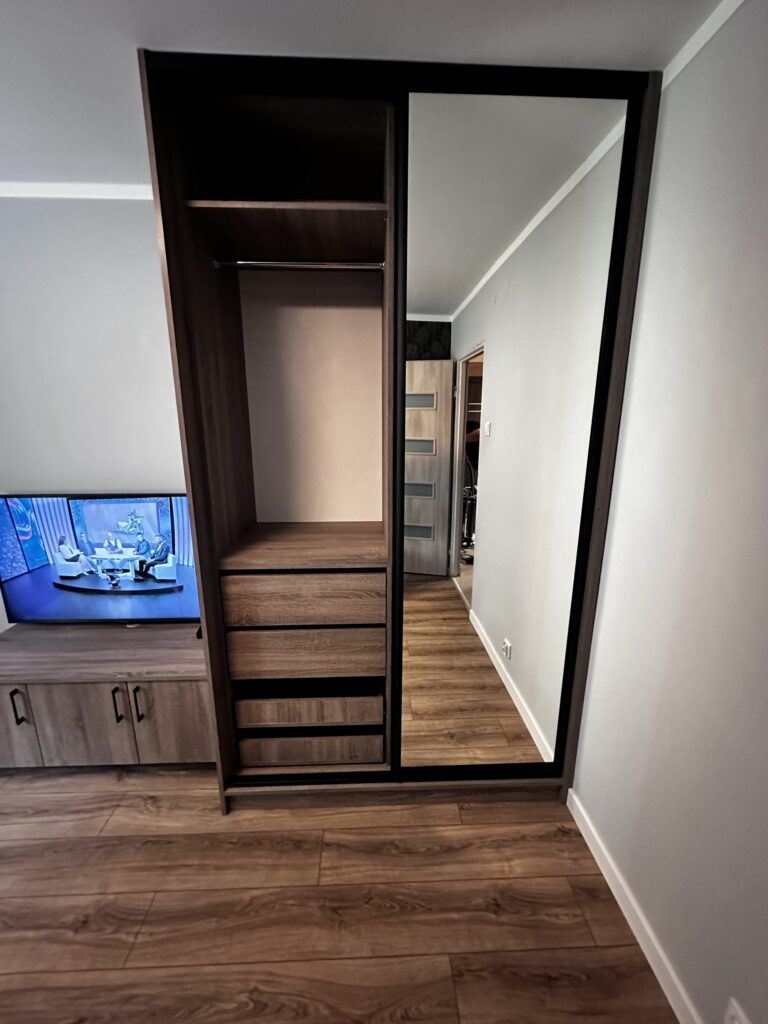 Szafa z lustrem, półkami i miejscem na telewizor.