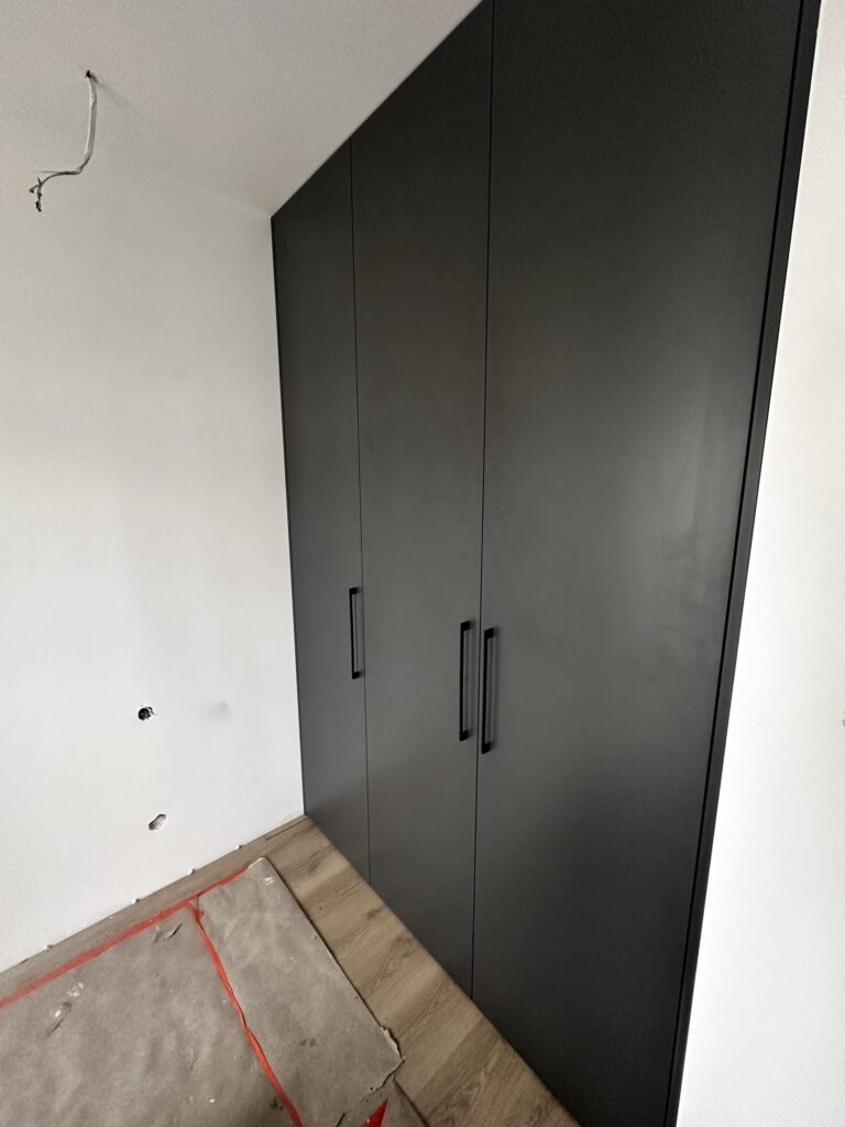 Ciemna zabudowa szafowa z długimi uchwytami.
