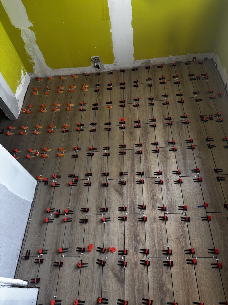 Instalacja ogrzewania podłogowego z czerwonymi klipsami.