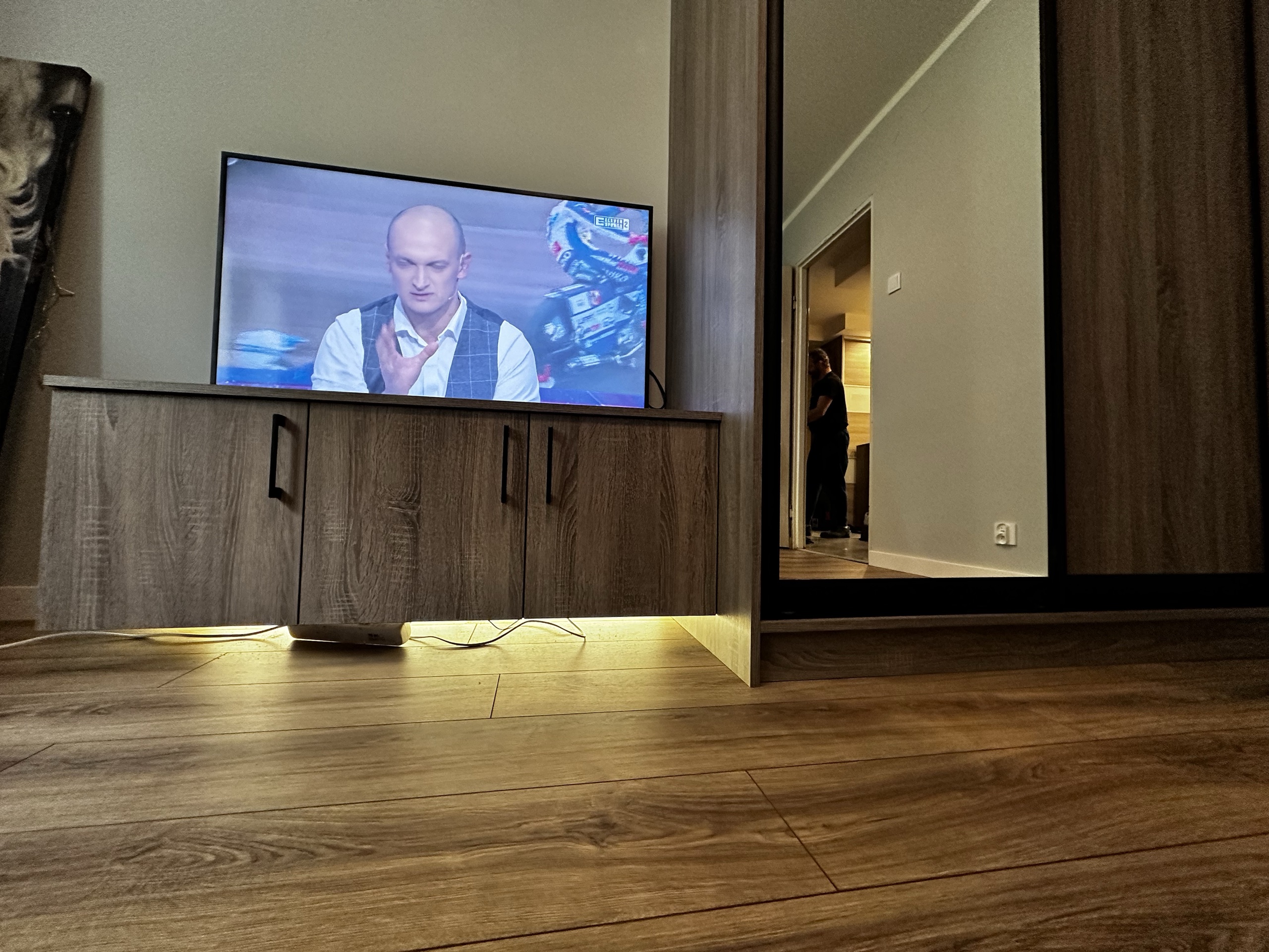 Telewizor na drewnianej szafce z podświetleniem.