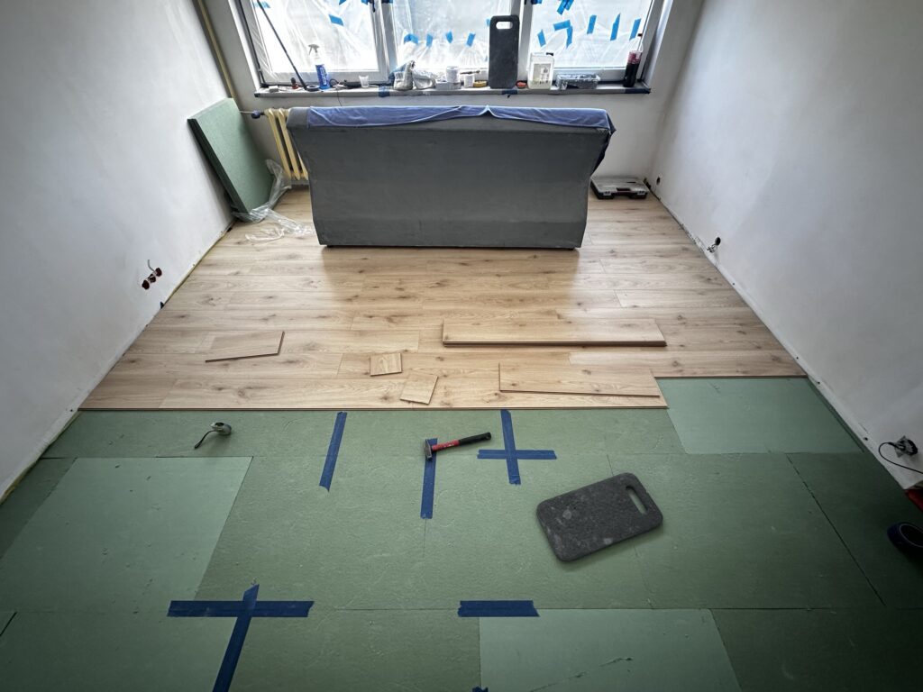 Montaż paneli podłogowych przy progu pokoju.