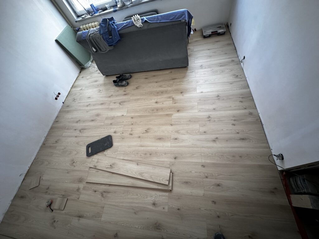 Układanie jasnych paneli podłogowych w remontowanym pokoju.