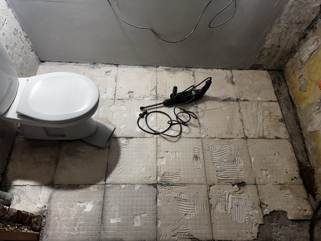 Łazienka z odkrytą podłogą i przewodami instalacyjnymi.