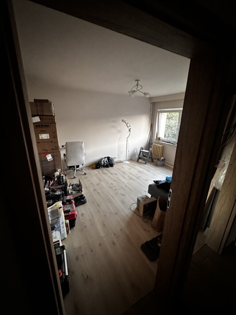Widok z korytarza na pokój z drewnianą podłogą.