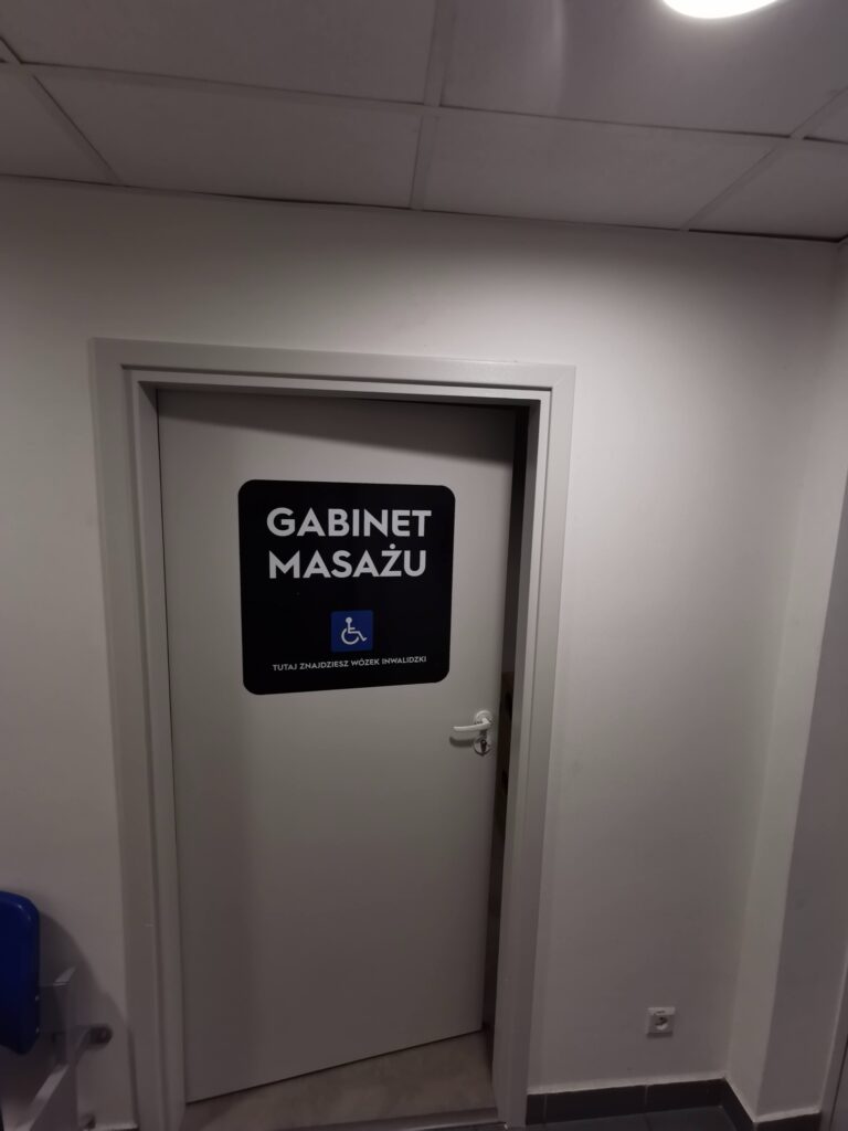 Szare drzwi z tabliczką „Gabinet masażu”.