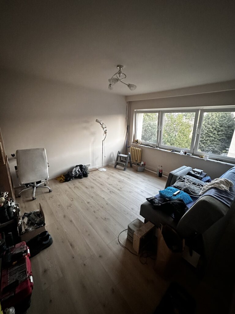 Salon z drewnianą podłogą i rzeczami podczas urządzania.