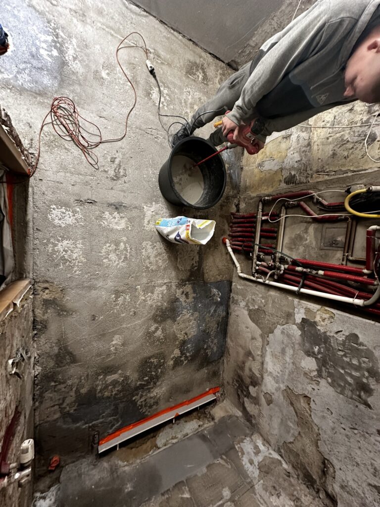 Prace przy rurze kanalizacyjnej w odkutej ścianie.
