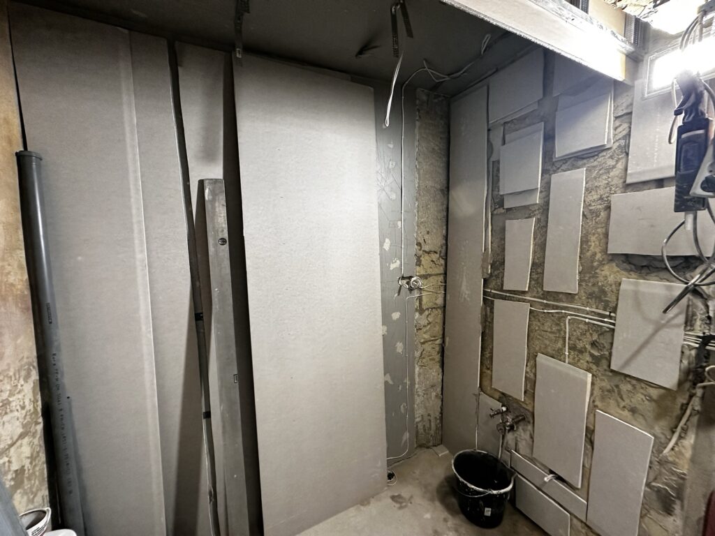 Fragment łazienki z odsłoniętymi profilami i instalacją.