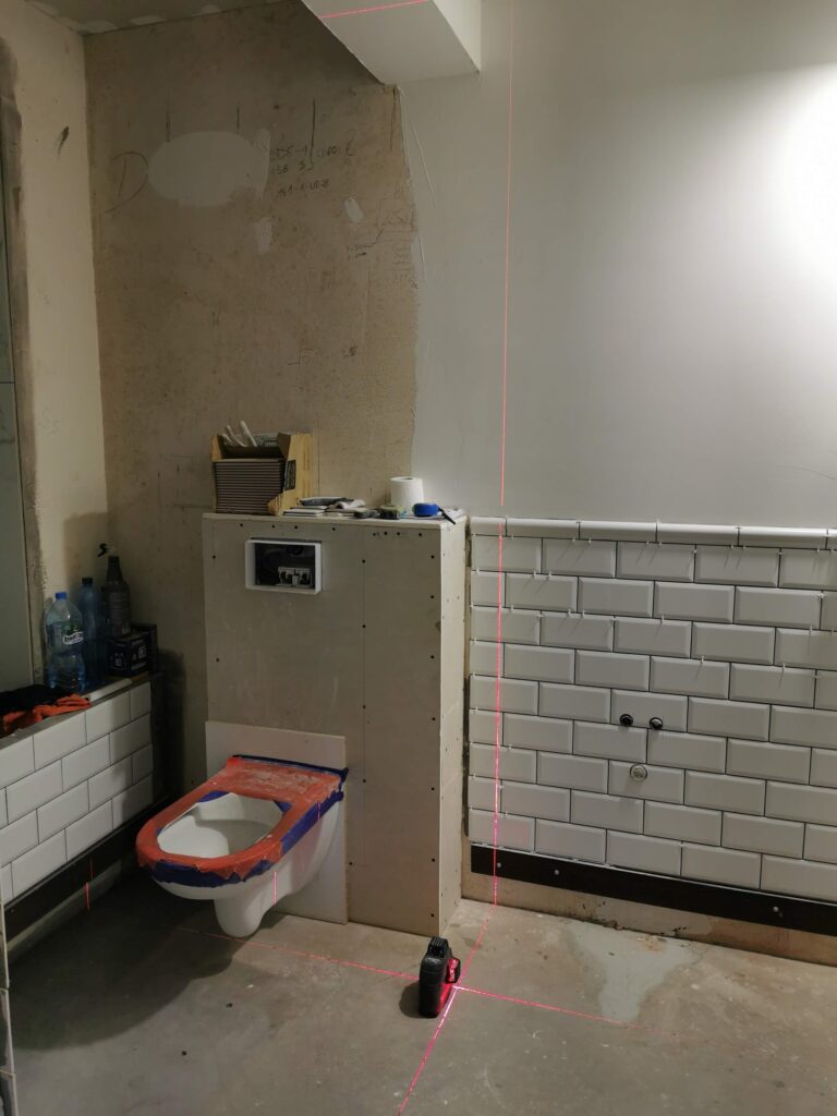 Remontowana łazienka z częściowo ułożonymi płytkami ściennymi