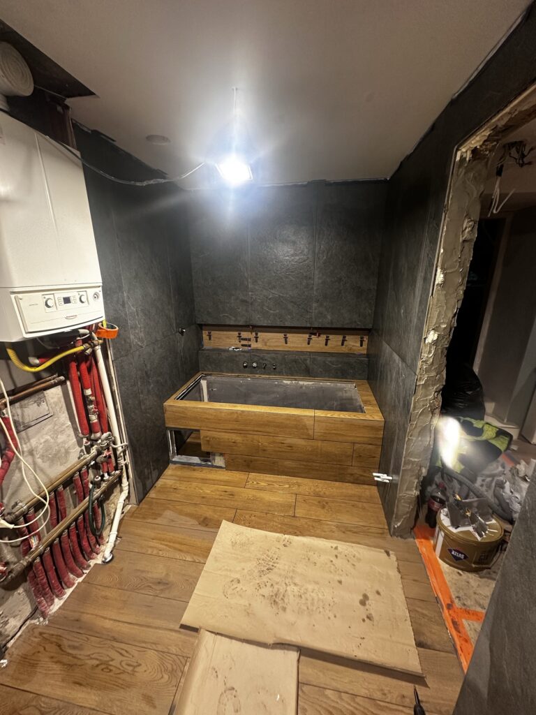 Remontowana łazienka z drewnianą zabudową i instalacjami.