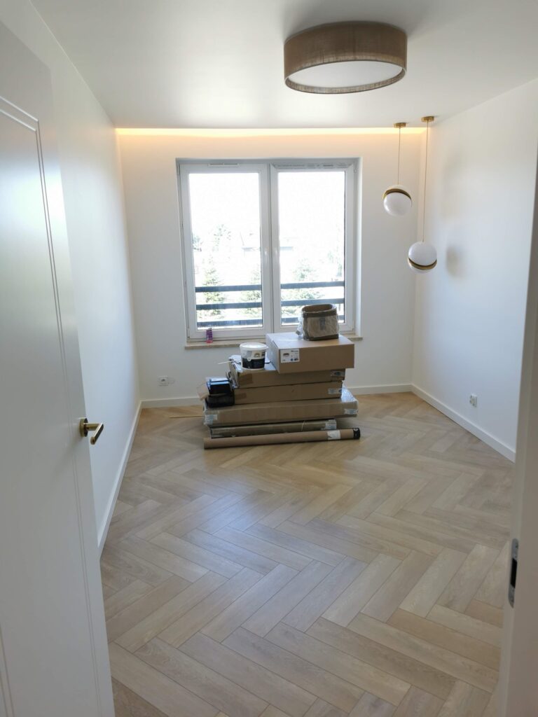 Jasny pokój z drewnianą podłogą, lampami i materiałami pod oknem