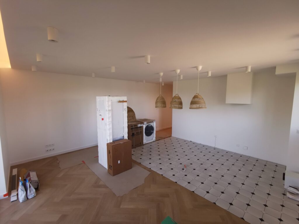 Remontowane wnętrze z geometryczną podłogą, sprzętami i lampami wiszącymi