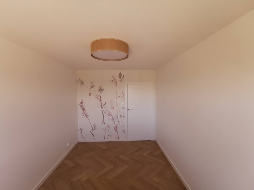Pusty pokój z drewnianym parkietem i kwiatowym motywem na ścianie