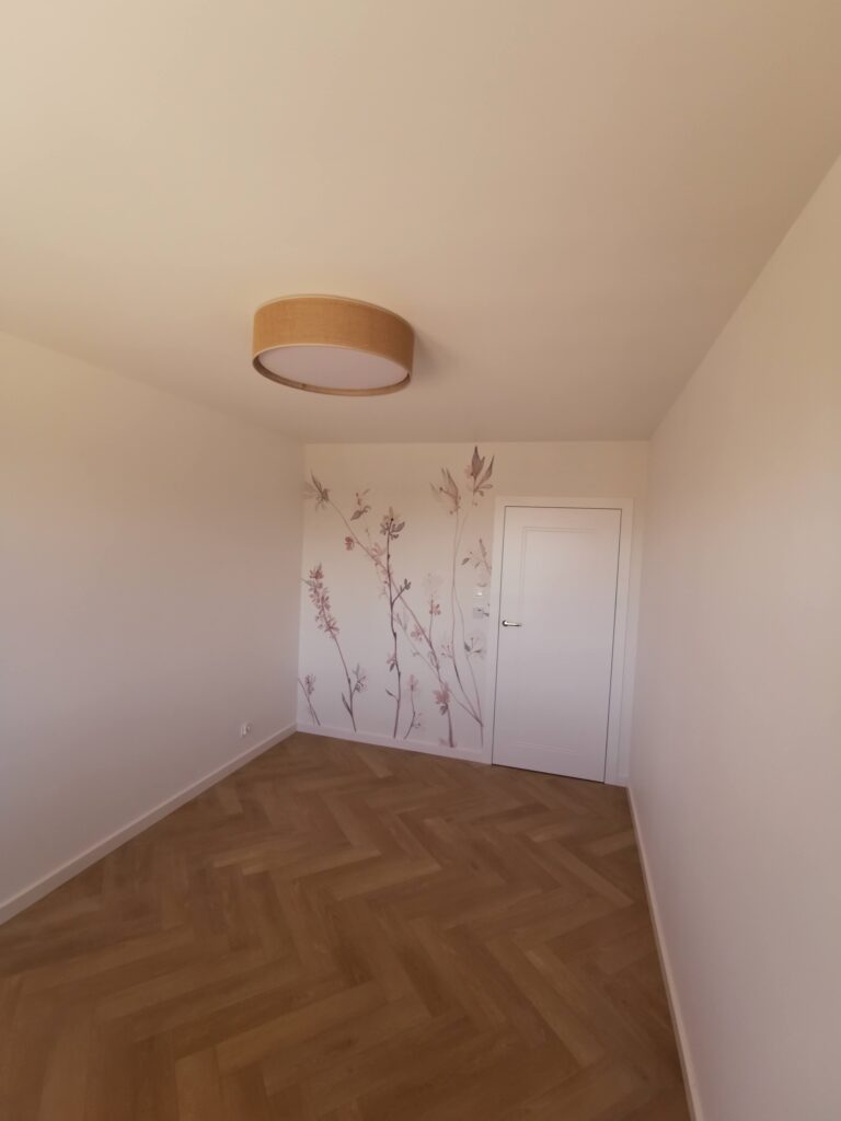 Jasny pusty pokój z parkietem i roślinną dekoracją ściany