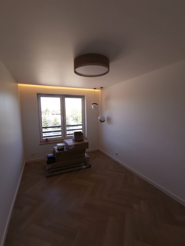 Pusty pokój z parkietem, dużym oknem i przygotowanymi materiałami