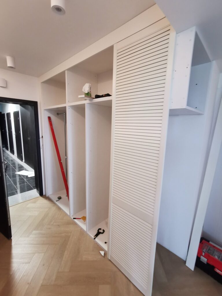 Montaż białej szafy z ażurowym frontem w przedpokoju