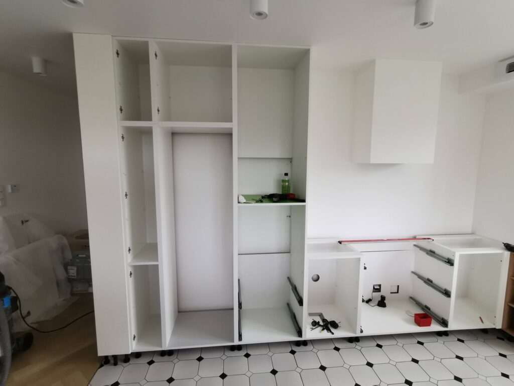 Biała zabudowa kuchenna bez frontów podczas montażu